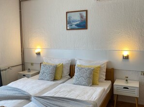A double bed with two nightstands, each with a lamp, in a room with textured walls and a framed picture above the bed. - Standard Twin 2 (Rakovica)