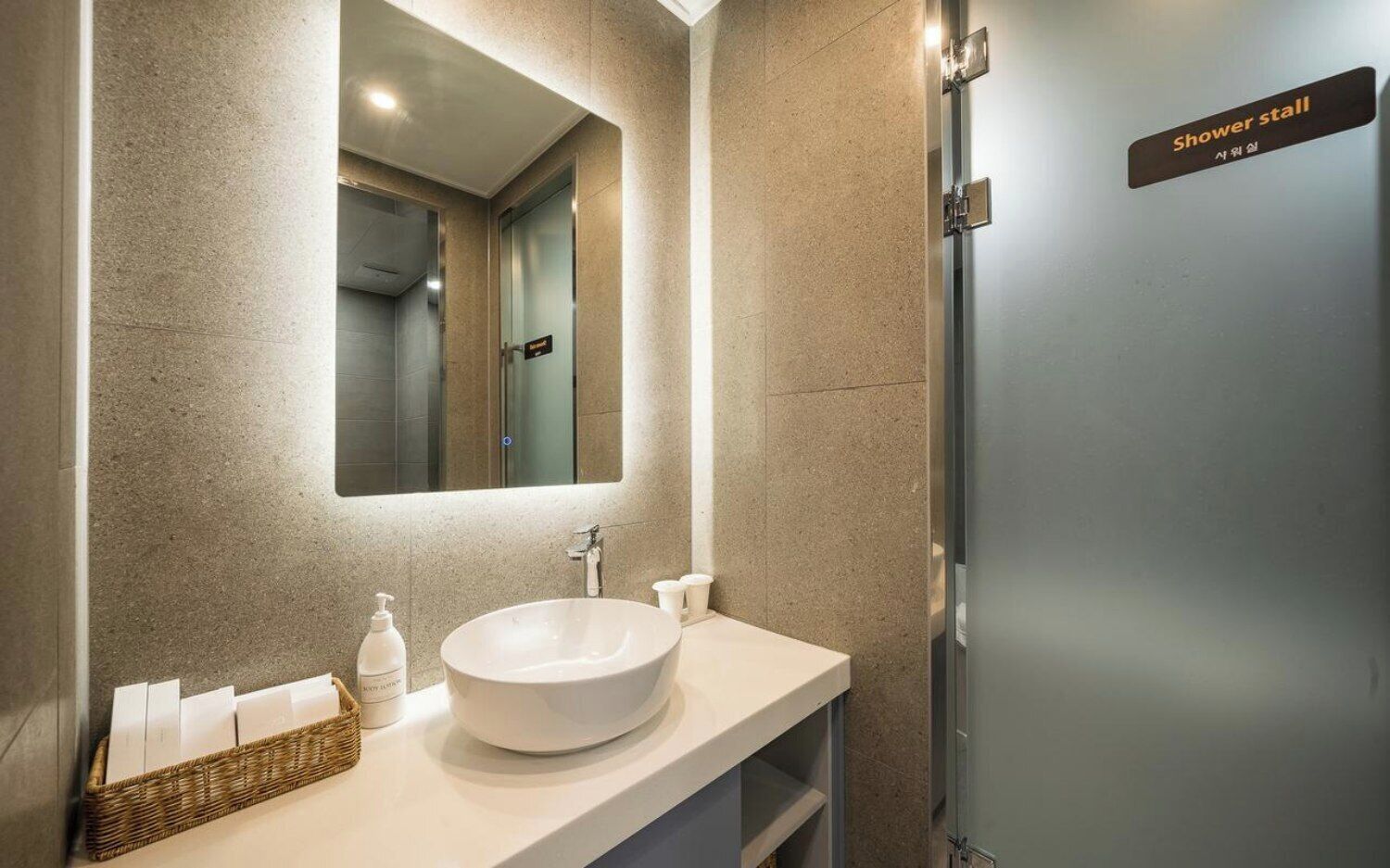 A modern bathroom with a large sink, a mirror, and a shower stall.