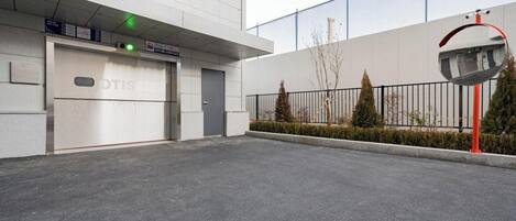 L’entrée d’un parking, avec une porte de garage fermée, un feu vert au-dessus et une caméra de surveillance sur le côté droit.
