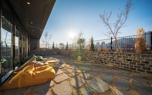 An outdoor patio with stone flooring, a yellow bean bag, and a small round table.