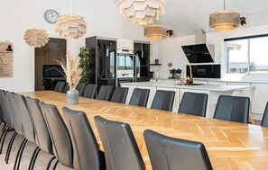 Eine moderne Küche mit einer zentralen Kochinsel, schwarzen Geräten und einem Essbereich mit einem langen Holztisch und Stühlen.