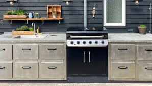 An outdoor kitchen with a built-in grill, storage cabinets, and a window with a view. - Pet friendly home in Harboøre with sauna (Harboøre)
