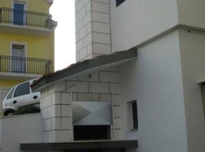 A modern building with a flat roof, a balcony, and a car parked in front. - Apartmani Cihorich - One Bedroom Apartment (Dugi Rat)