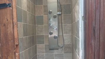 Un espace douche avec un mur carrelé, une douchette à main et un robinet à main.