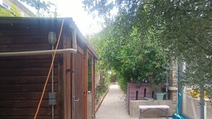 Eine Holzhütte mit Tür, einer Bank und einem Weg, der in einen Garten führt.