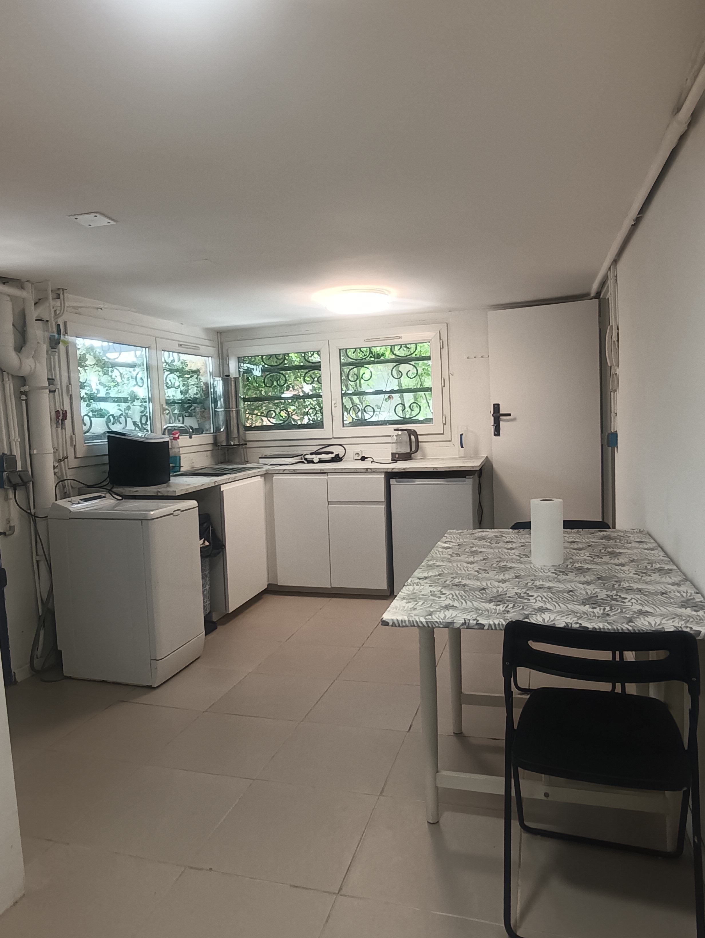 Une cuisine de taille réduite comprenant une table à manger, des chaises et un réfrigérateur.