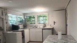 Eine kleine Küche mit Esstisch, Stühlen und einem Kühlschrank.