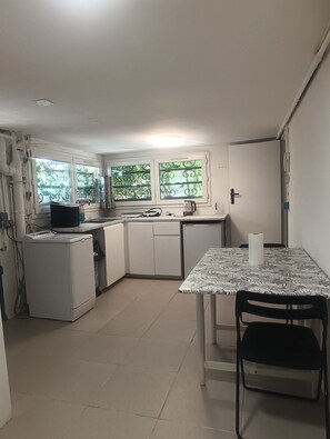 A compact kitchen with a dining table, chairs, and a refrigerator. - Private Heated Pool & Sauna – Ground-Floor Accommodation Near Paris (Seine-et-Marne)