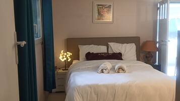 A bedroom with a bed, a nightstand, a lamp, and a window with curtains.
