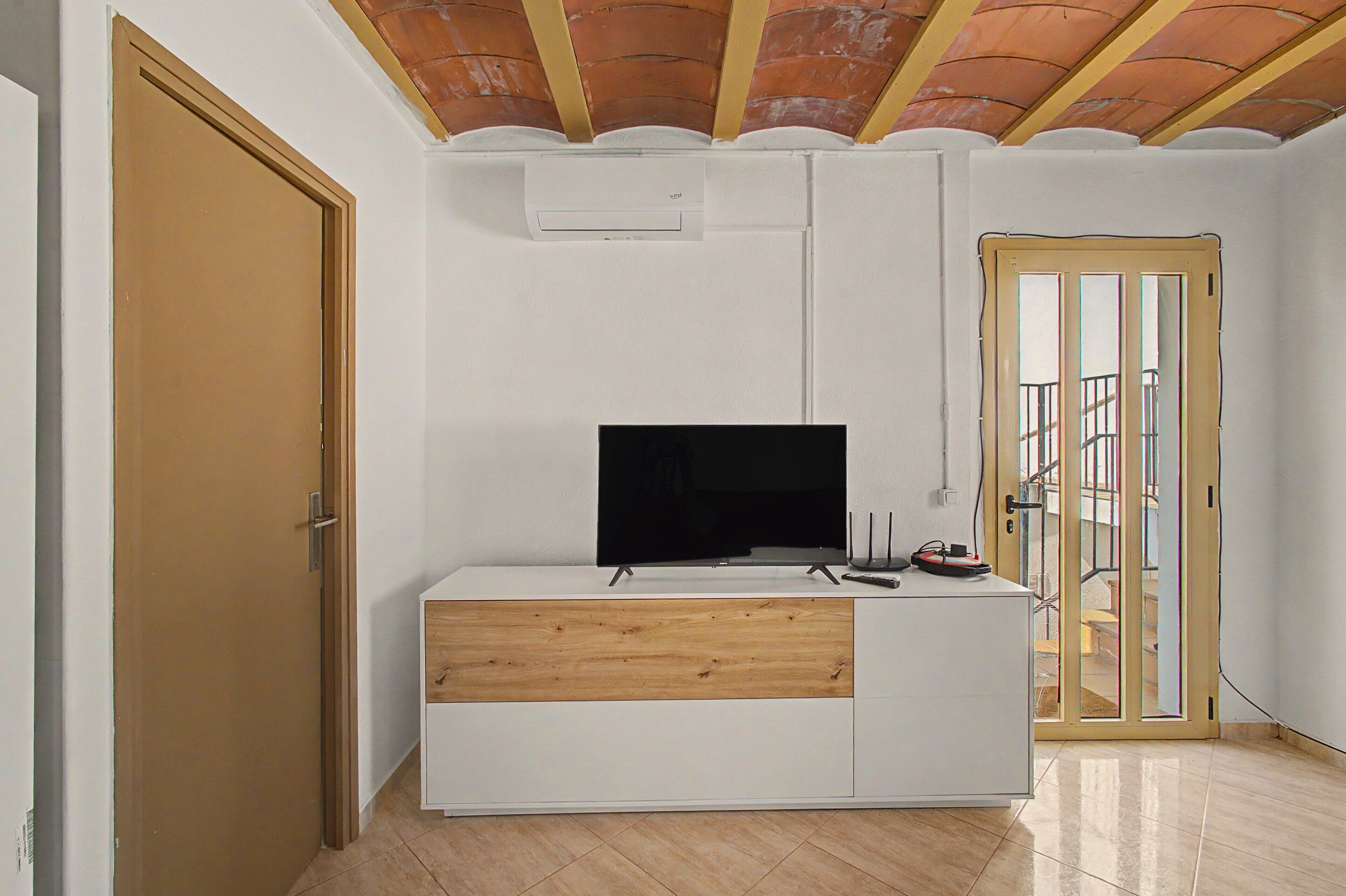 A room with a white entertainment unit, a television, and a wooden cabinet.