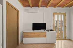 A room with a white entertainment unit, a television, and a wooden cabinet.