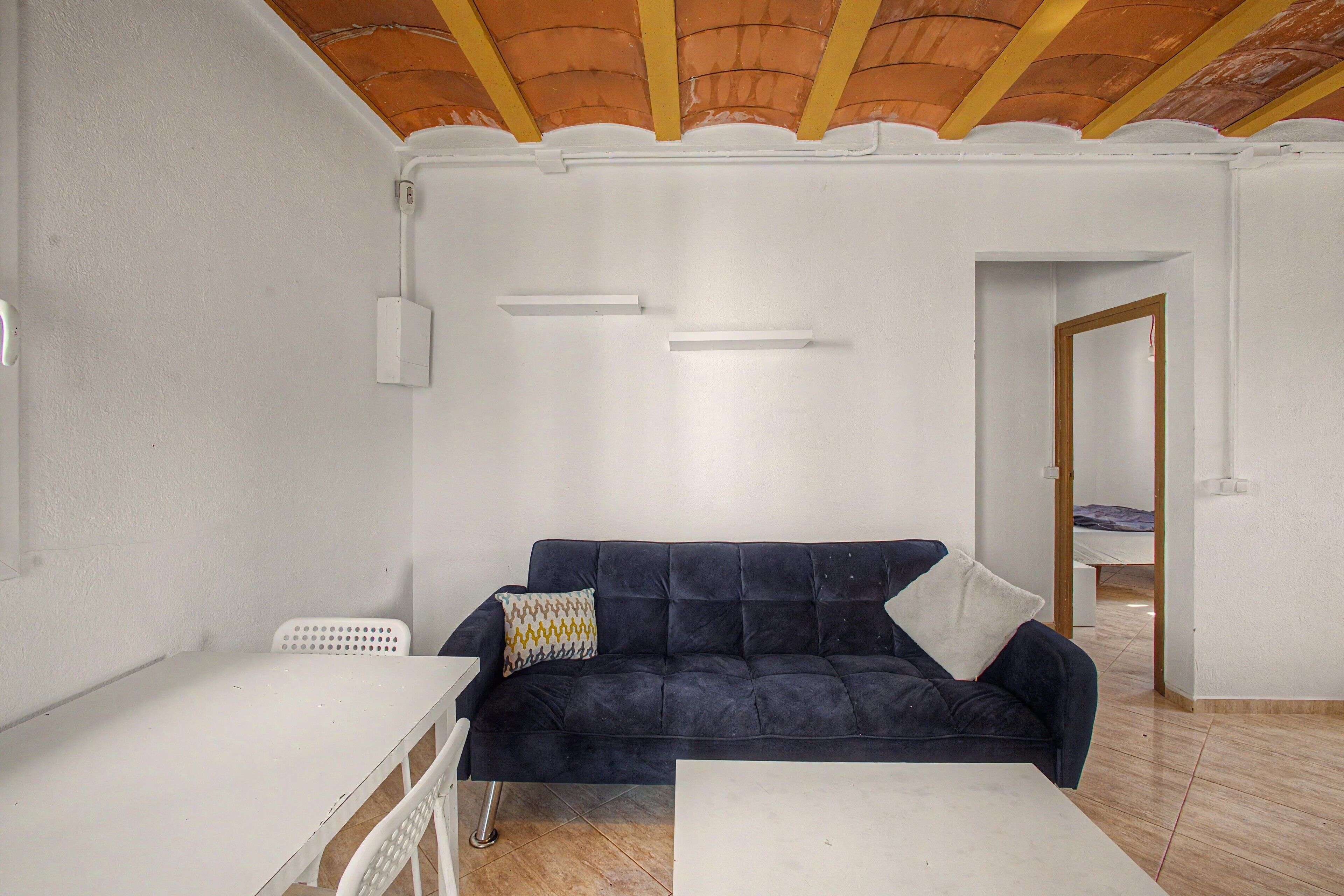 A room with a dark blue sofa, a white table, and a tiled floor.