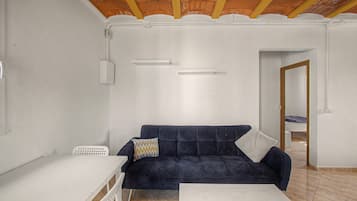A room with a dark blue sofa, a white table, and a tiled floor.