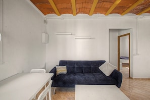 A room with a dark blue sofa, a white table, and a tiled floor.