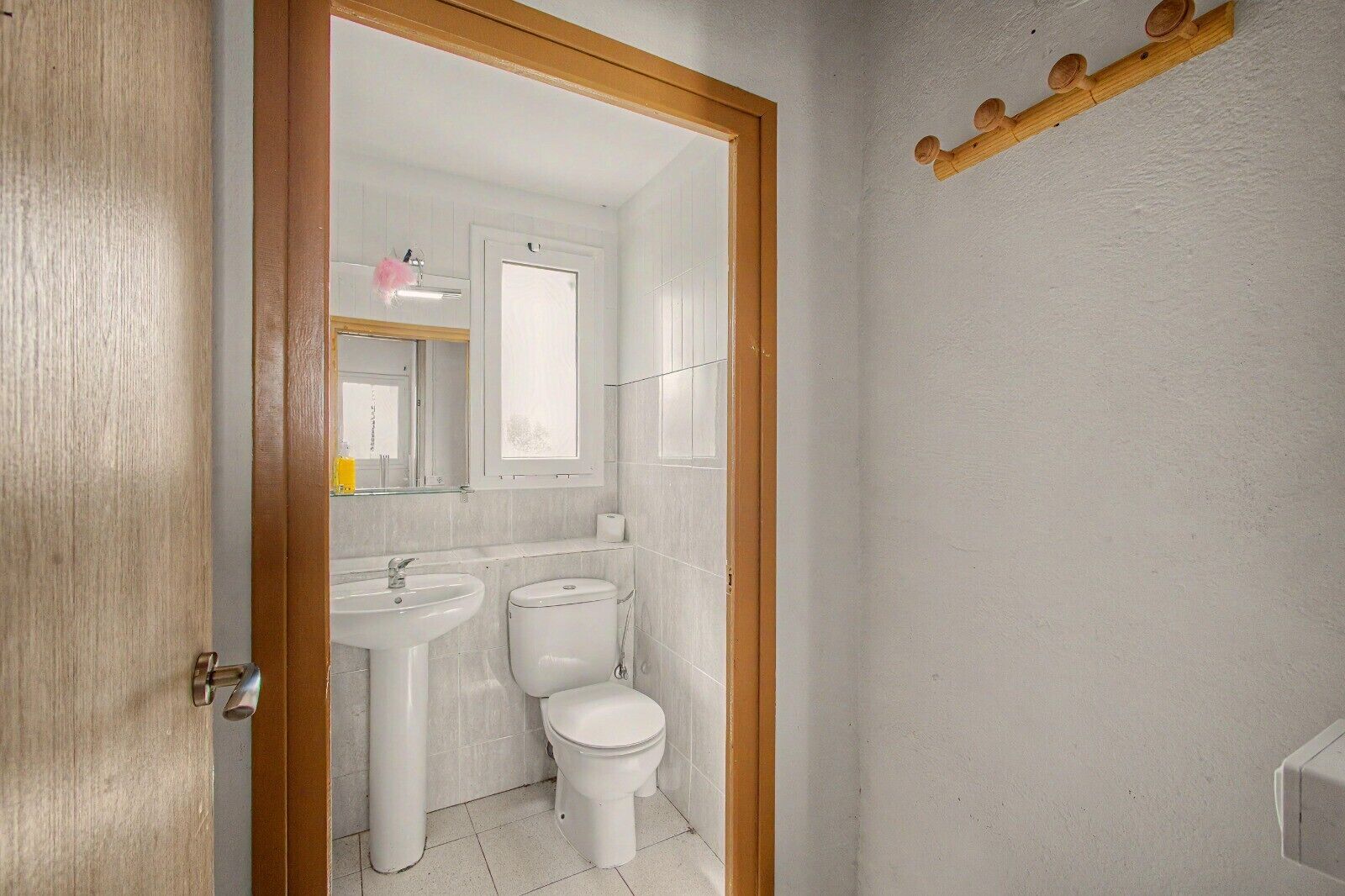 Un baño con puerta de madera, dos lavamanos y un inodoro.