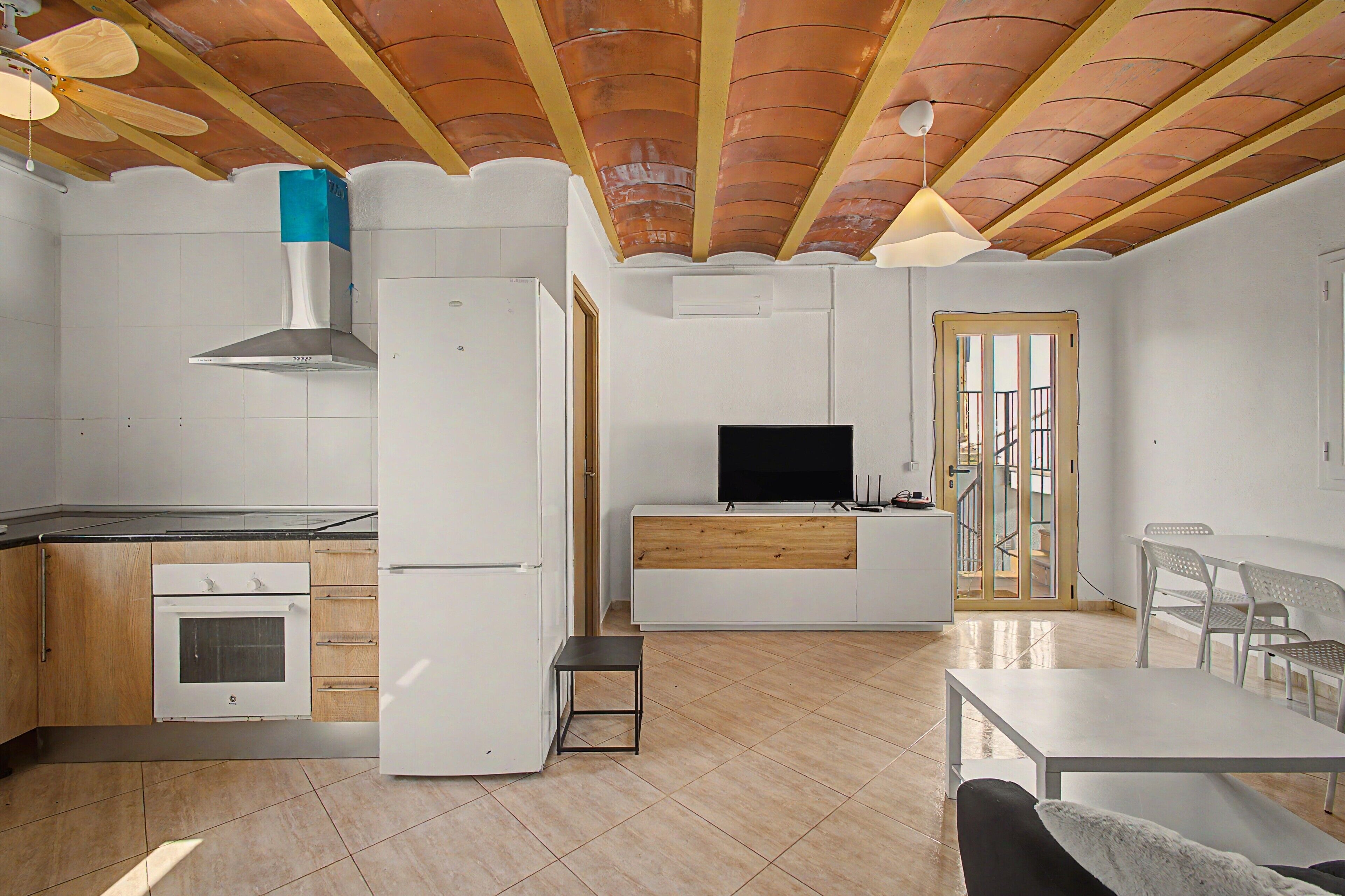 Una cocina compacta con horno integrado, un refrigerador blanco y un mueble de madera.