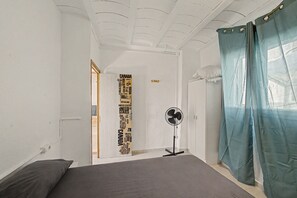 Et soveværelse med seng, en ventilator og en dør med et verdenskort.