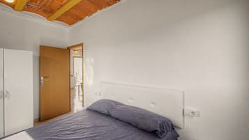 A bedroom with a bed, a wardrobe, and a door leading to another room.