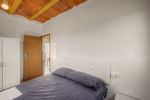 A bedroom with a bed, a wardrobe, and a door leading to another room.