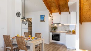 A modern kitchen with white cabinets, a built-in oven, and a wooden ceiling. - Apartment M&K - Two Bedroom Apartment With Balcony and Sea View (Zupa dubrovacka)