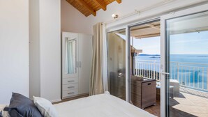 A bedroom with a bed, a wardrobe, and a sliding glass door leading to a balcony with a view of the sea. - Apartment M&K - Two Bedroom Apartment With Balcony and Sea View (Zupa dubrovacka)