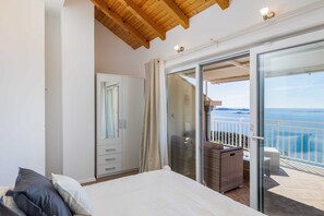 A bedroom with a bed, a wardrobe, and a sliding glass door leading to a balcony with a view of the sea. - Apartment M&K - Two Bedroom Apartment With Balcony and Sea View (Zupa dubrovacka)