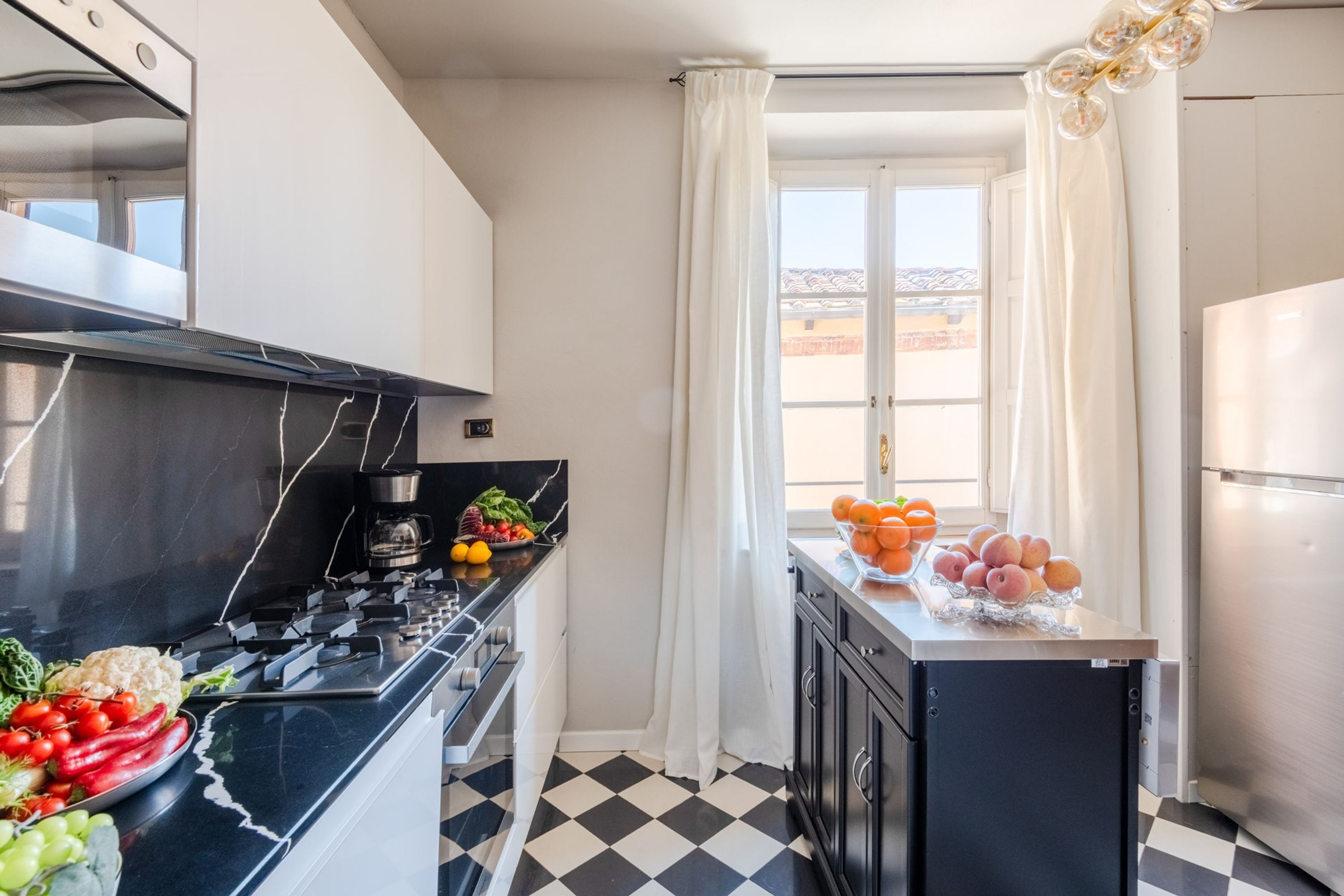 A kitchen with a black stove, a coffee maker, and a fruit bowl on the counter.