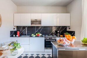 Eine moderne Küche mit weißen Schränken, einer schwarzen Marmor-Spritzschutzwand und Edelstahlgeräten.