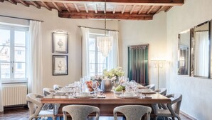 A dining room with a wooden table set for a meal, surrounded by upholstered chairs. - The Tuscan Serenade in Lucca (Lucca)