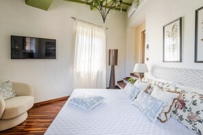 A bedroom with a bed, a chair, a TV, and a lamp. - The Tuscan Serenade in Lucca (Lucca)