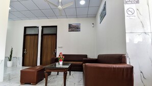 Ein modernes Interieur mit einem Glastisch, Ledersofas, einem Blumentopf und einem Deckenventilator.