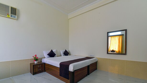 Ein Hotelzimmer mit Bett, Nachttisch und Spiegel an der Wand.