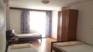 Una camera d'albergo con due letti, un armadio, una scrivania con una sedia e una televisione.
