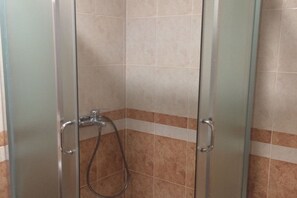 A shower enclosure with a glass door, a showerhead, and a handheld shower hose. - Apartments Aleksić, Bečići - Studio Apartment with Terrace 1 (Becici)