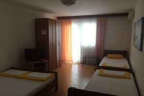 Ein Hotelzimmer mit zwei Einzelbetten, einem Fernseher, einem Kleiderschrank und einem Sessel.