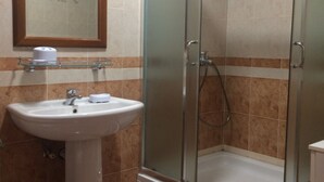 Ein Badezimmer mit Duschkabine, Waschbecken und Spiegel sowie Toilette.