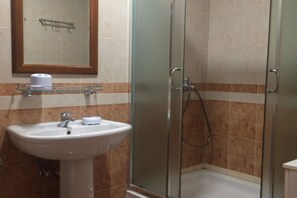 Ein Badezimmer mit Duschkabine, Waschbecken und Spiegel sowie Toilette.