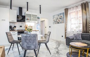 A modern living room with a grey sofa, a round coffee table, and a dining area with a white table and grey chairs. - Beautiful home in Lepoglava with WiFi (Lepoglava)