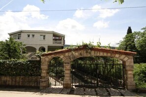 A gated entrance with a stone archway leading to a building with a balcony. - Apartments Roza - One Bedroom Apartment with Garden and Sea View (Herceg Novi)