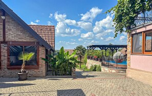 A courtyard with a brick building, a swimming pool, and potted plants.