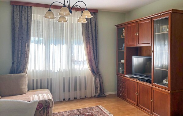 A living room with a sofa, a television on a wooden cabinet, and a patterned rug.
