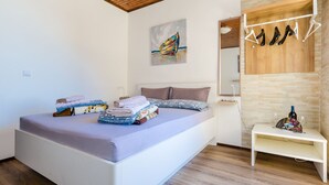 Une chambre moderne avec un lit, un plafond en bois, un tableau, un porte-manteau et une petite table sur laquelle se trouve une bouteille de vin.
