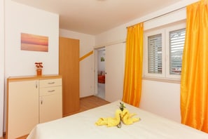 Ein Schlafzimmer mit einem Bett, einem Holzschrank, einem Gemälde an der Wand und einem Fenster mit Vorhängen.