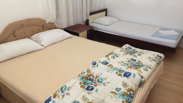A hotel room with a bed, a nightstand, and a small table. - Apartments Roza - Standard Double Room with Shared Bathroom (Herceg Novi)