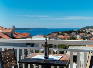A balcony with a table, two wine glasses, and a bottle of wine. - Apartments Trogrlic - Studio With Balcony and Sea View (Hvar)