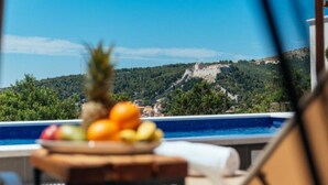 Vista da piscina, com uma cesta de frutas e a paisagem de um castelo no alto da colina.
