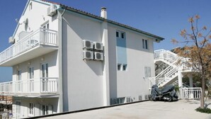 Um edifício de dois andares com varanda, aparelhos de ar condicionado e escadaria que leva a um andar superior.