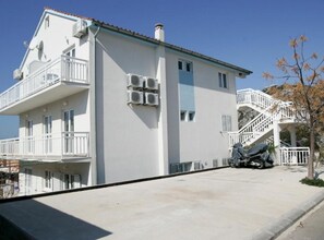 A two-story building with a balcony, air conditioning units, and a staircase leading to an upper floor. - Apartments Trogrlic - Studio With Balcony and Sea View (Hvar)