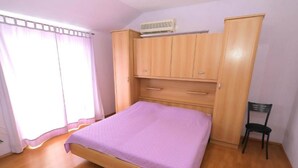 Quarto com cama, guarda-roupa de madeira e uma cadeira.