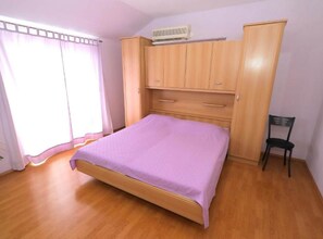 A bedroom with a bed, wooden wardrobe, and a chair. - Apartments Trogrlic - Studio With Balcony and Sea View (Hvar)